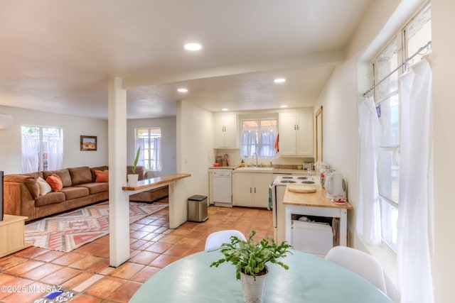 kitchen featuring white appliances, a healthy amount of sunlight, a sink, light countertops, and white cabinetry