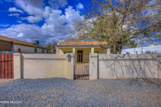 view of gate with a fenced front yard and central AC unit