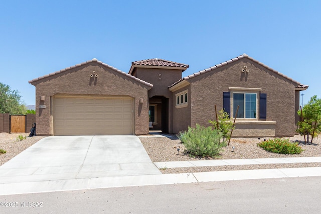 mediterranean / spanish house with stucco siding, fence, concrete driveway, a garage, and a tiled roof