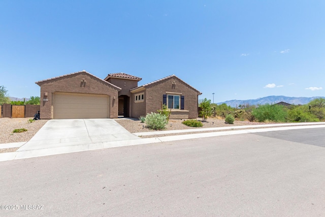 mediterranean / spanish-style house featuring an attached garage, concrete driveway, a tile roof, stucco siding, and a mountain view