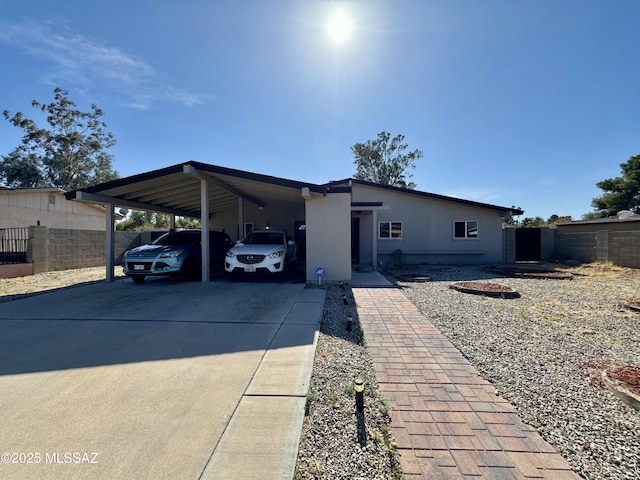 view of front of home featuring a carport, concrete driveway, and fence