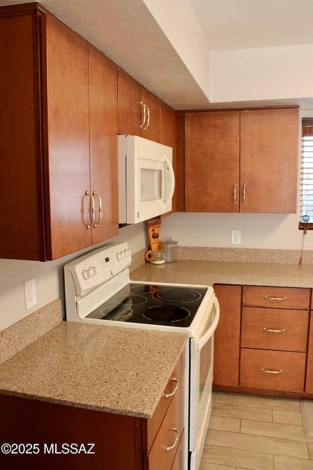 kitchen with light wood-type flooring, white appliances, brown cabinets, and light stone countertops