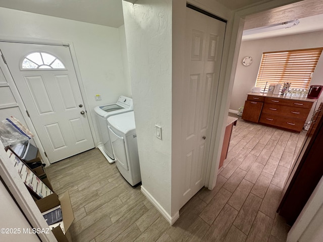 washroom featuring laundry area, washing machine and clothes dryer, baseboards, and wood finish floors