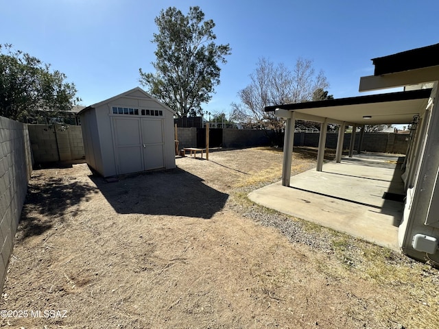 view of yard with an outbuilding, a storage shed, a fenced backyard, and a patio area