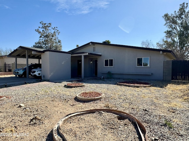 view of front facade featuring a carport, concrete driveway, and fence