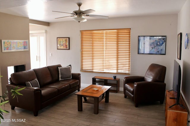 living room with baseboards, ceiling fan, and wood finished floors