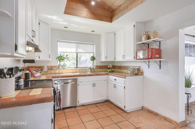 kitchen with a tray ceiling, a sink, open shelves, tile counters, and stainless steel dishwasher