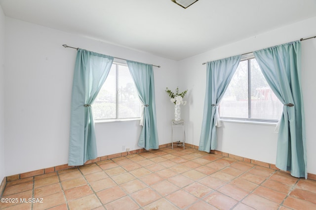 spare room with baseboards and light tile patterned floors