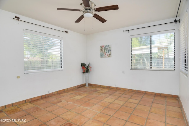 unfurnished room with baseboards, light tile patterned floors, a ceiling fan, and plenty of natural light