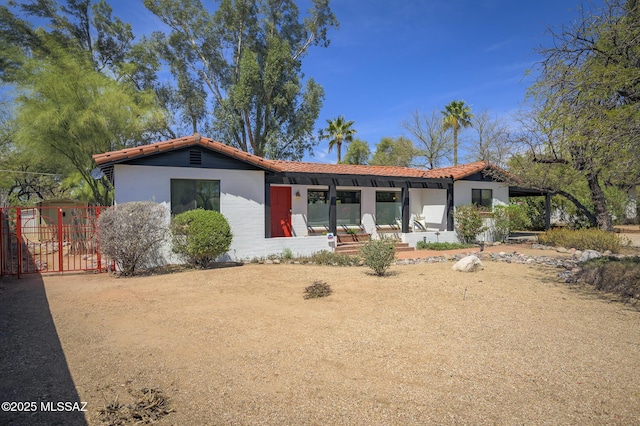 view of front of house featuring a tile roof and a gate