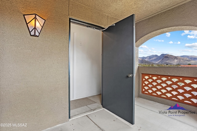 doorway to property featuring a balcony, a mountain view, and stucco siding