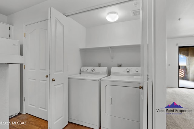 washroom featuring washer and dryer, laundry area, wood finished floors, and visible vents