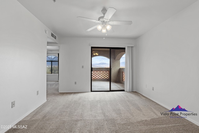 spare room featuring baseboards, visible vents, carpet floors, and ceiling fan