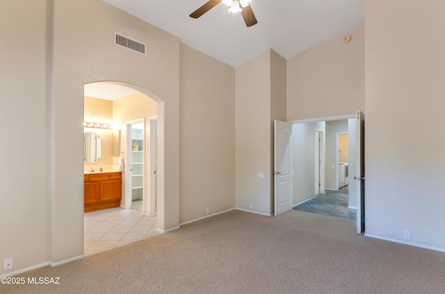 11092 N Eagle Crest Dr, Tucson, AZ 85737 - unfurnished bedroom with arched walkways, a towering ceiling, light colored carpet, baseboards, and ensuite bathroom