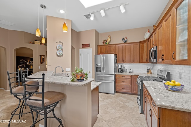 kitchen with stainless steel appliances, brown cabinets, backsplash, and a breakfast bar