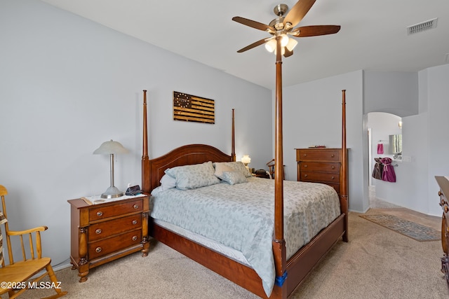 bedroom with arched walkways, visible vents, light colored carpet, and a ceiling fan