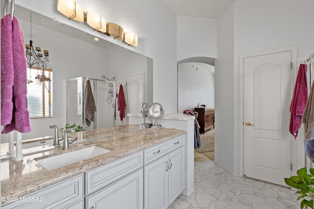 bathroom featuring vanity, a shower stall, and an inviting chandelier