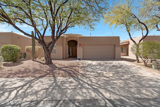 view of front of house featuring a tile roof, concrete driveway, a garage, and stucco siding