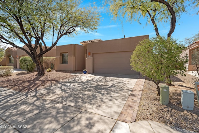 adobe home with a garage, driveway, and stucco siding