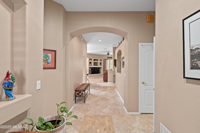 hall with baseboards and arched walkways