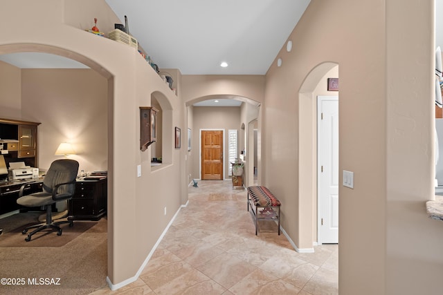 hall with recessed lighting, baseboards, and arched walkways