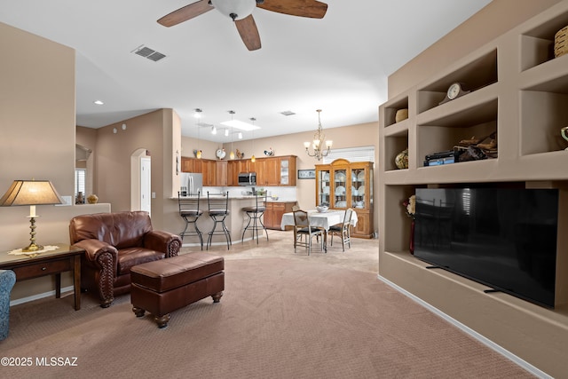 living area featuring visible vents, built in shelves, baseboards, light carpet, and arched walkways