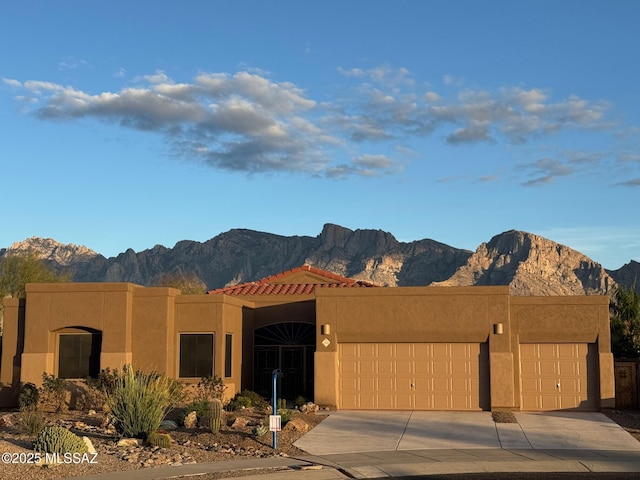 view of front of house with concrete driveway, a mountain view, a garage, and stucco siding