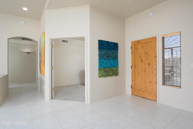 interior space featuring light tile patterned floors, visible vents, and arched walkways