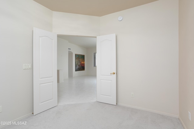 spare room with light carpet and baseboards