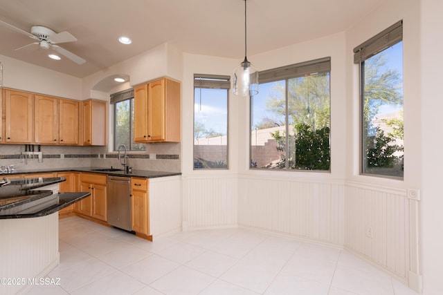 kitchen featuring a wainscoted wall, light brown cabinetry, a sink, pendant lighting, and dishwasher