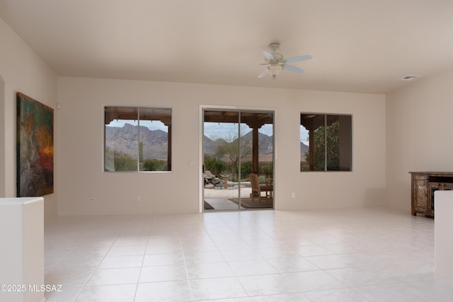 tiled spare room with visible vents, a mountain view, and ceiling fan