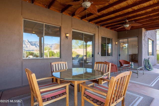 exterior space with beam ceiling, a mountain view, concrete floors, wood ceiling, and ceiling fan