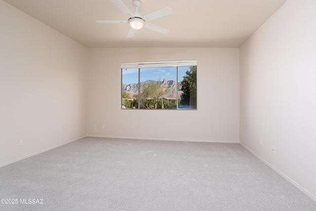 spare room with a ceiling fan, baseboards, and light carpet