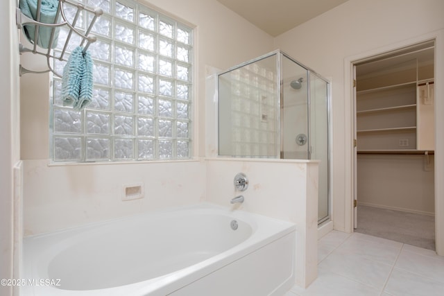 full bath featuring tile patterned flooring, a garden tub, a spacious closet, and a stall shower