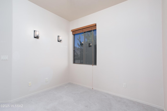 spare room featuring light carpet and baseboards