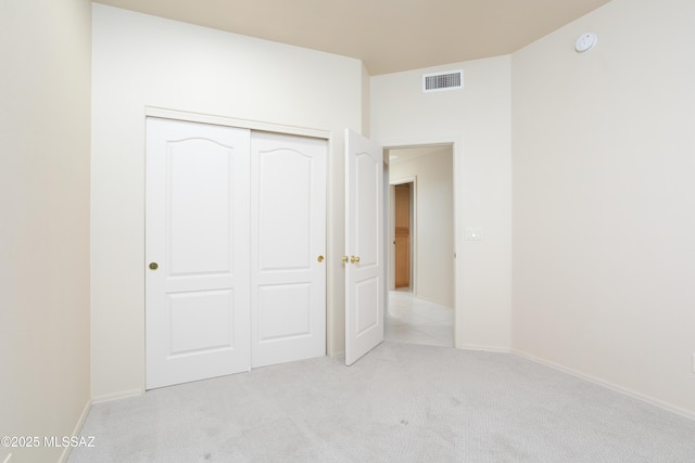 unfurnished bedroom featuring baseboards, visible vents, light carpet, and a closet