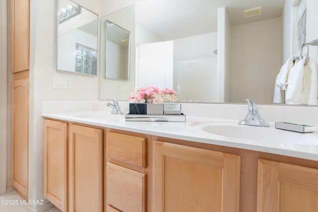 full bath featuring double vanity, visible vents, and a sink