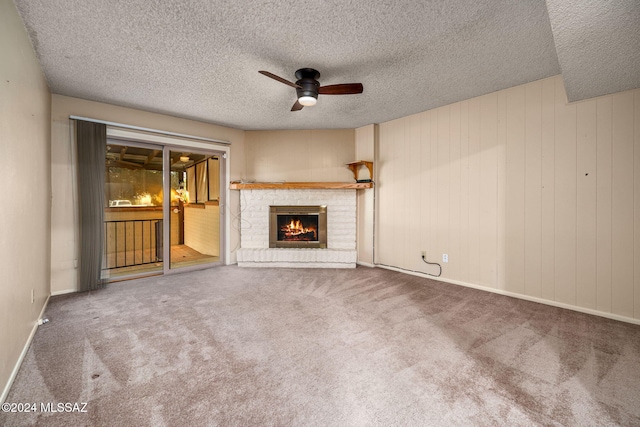 unfurnished living room with a ceiling fan, a textured ceiling, carpet floors, a fireplace, and baseboards