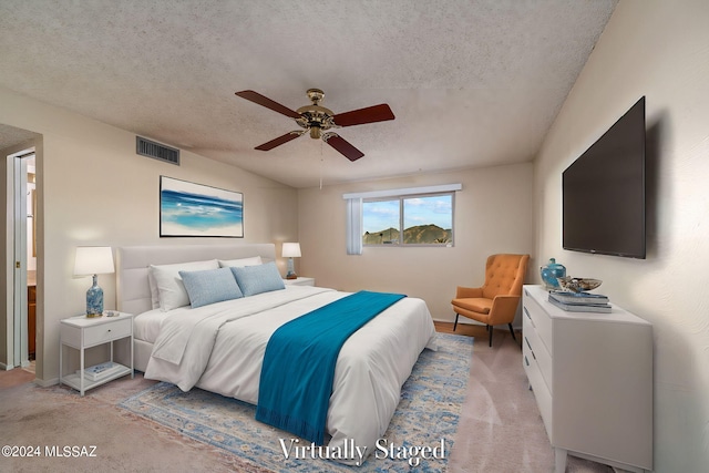 bedroom with a textured ceiling, a ceiling fan, visible vents, and light carpet