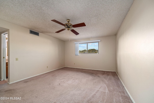 empty room featuring visible vents, carpet floors, a textured ceiling, and baseboards