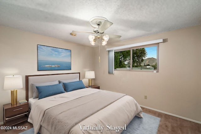 bedroom featuring baseboards, carpet floors, a textured ceiling, and a ceiling fan