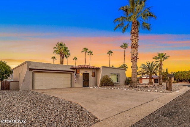 view of front of house featuring stucco siding, concrete driveway, a garage, and fence