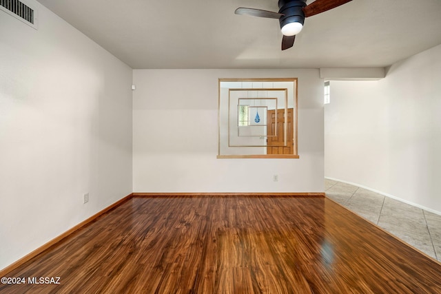 spare room featuring ceiling fan, wood finished floors, visible vents, and baseboards