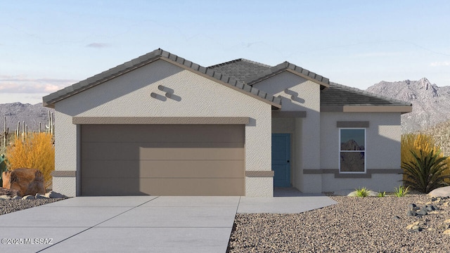 view of front facade with a tiled roof, concrete driveway, stucco siding, a garage, and a mountain view