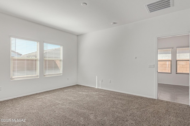 empty room featuring tile patterned floors, visible vents, baseboards, and carpet flooring