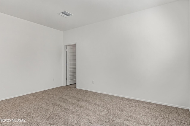 carpeted spare room with visible vents and baseboards