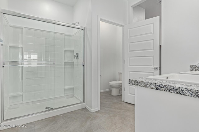 bathroom featuring baseboards, vanity, toilet, and a shower stall