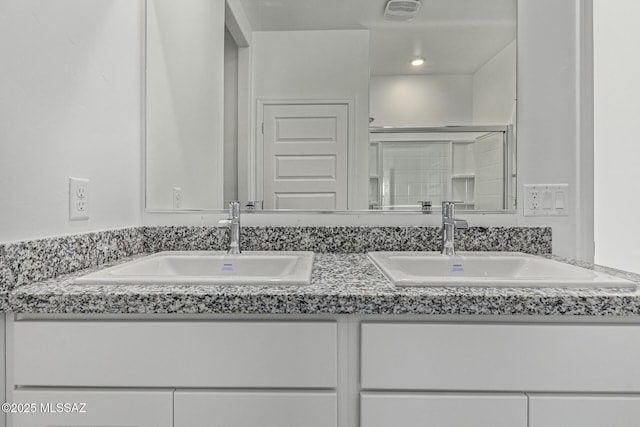 full bathroom with a shower stall, double vanity, visible vents, and a sink