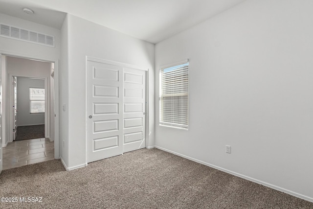 unfurnished bedroom featuring a closet, carpet flooring, baseboards, and visible vents