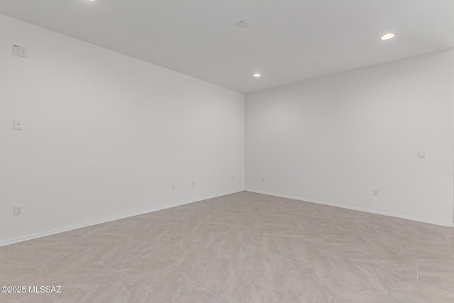 spare room featuring recessed lighting and baseboards